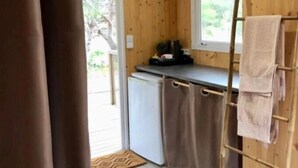 Ett litet, praktiskt kök med träväggar, ett litet kylskåp, ett fönster och en handduksställning.