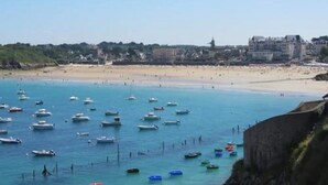 A coastal view with boats on the water and a beach with buildings in the background. - ZEcamping 1 étoile 5km plage mobil-home BBQ 20m2 2 pers (Plessix-Balisson)