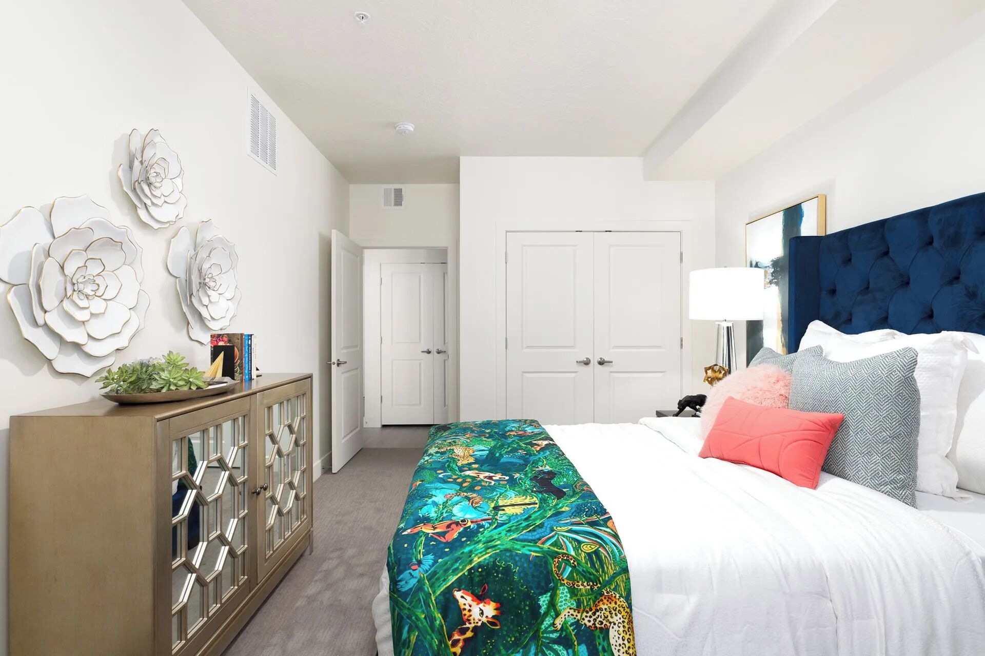 A bedroom with a bed, a dresser, a door, and a wall with decorative flowers.