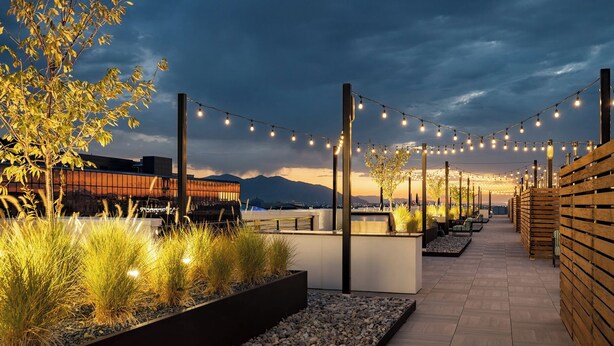A rooftop terrace with string lights, seating areas, and a view of the cityscape. - Upscale Condo at the Center of It All (Salt Lake City)