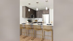 A modern kitchen with wooden cabinets, a white countertop, and three gold wire mesh bar stools. - Upscale Condo at the Center of It All (Salt Lake City)