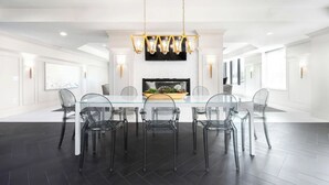 A spacious dining area with a glass table and chairs, a modern chandelier, and a flat-screen TV above the table. - Upscale Condo at the Center of It All (Salt Lake City)