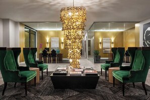 Un vestíbulo con sillas tapizadas en verde, una mesa de centro negra y una lámpara decorativa.