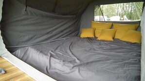 Une tente équipée d’un lit, d’oreillers et d’une fenêtre.