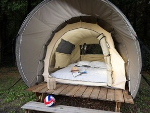 A dome-shaped tent with a bed inside, a picnic table, and a volleyball. - ZEcamping 3 étoiles locatif 2 pers (Bagneaux-sur-Loing)