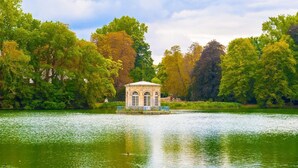 Un belvédère au bord d’un lac, entouré d’arbres.