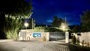 Une entrée fermée par un portail mène à une propriété sur laquelle est apposée une plaque indiquant : « LA RIVIÈRE DORÉE ».