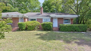 A two-story brick house with a front porch, a chimney, and a well-maintained lawn. - Modern 2BR Steps to St Francis (Columbus)