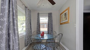 A dining area with a glass table, metal chairs, a ceiling fan, and a framed picture on the wall. - Modern 2BR Steps to St Francis (Columbus)