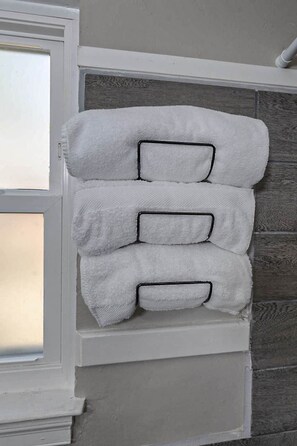 A wall-mounted towel rack with three white towels.