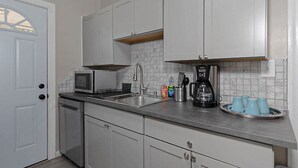 A kitchen with white cabinets, a microwave, a coffee maker, and a sink. - Modern 2BR Steps to St Francis (Columbus)