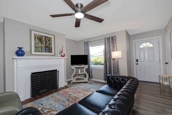 Una sala de estar con chimenea, televisor, sofá y ventilador de techo.