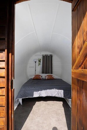 Een knus, rond vertrek met een bed, een lamp en een raam.
