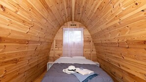 Un dormitorio acogedor en el ático, con paredes de madera y techo inclinado.