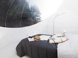 A tent-like room with a bed, a hat, and a book. - ZEcamping 3 étoiles chiens acceptés locatif 2 pers (Bagneaux-sur-Loing)