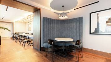 A modern interior with a round table, chairs, a ceiling light, and a framed picture on the wall.