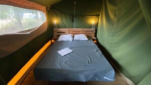 Een tentkamer met een bed, kussens en een raam.