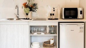 Une cuisine compacte équipée d’un four à micro-ondes, d’un évier et d’étagères de rangement.