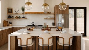 A modern kitchen with a central island, wooden cabinets, and pendant lighting. - Solara Ridge • Serene Escape, Panoramic Views, Spa, and Cowboy Tub (Yucca Valley)