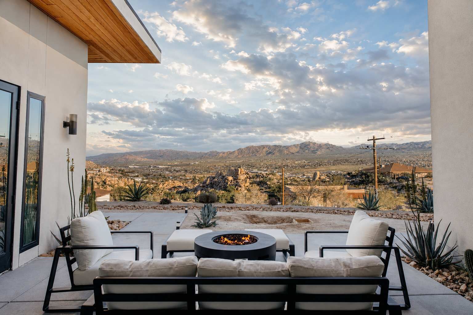 Un patio al aire libre con una chimenea, asientos y vistas a un paisaje desértico.