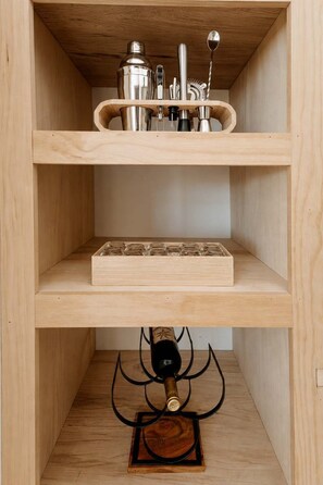 Ein Regalschrank aus Holz mit Küchenutensilien und einer Weinflasche.