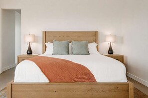 A bed with a wooden headboard, two bedside lamps, and a throw blanket. - Solara Ridge · Hilltop Views, Hot Tub, Cowboy Tub (Yucca Valley)