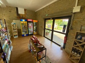 Une pièce avec un mur en pierre, un réfrigérateur Coca-Cola, un bar à collations et une étagère à vin.