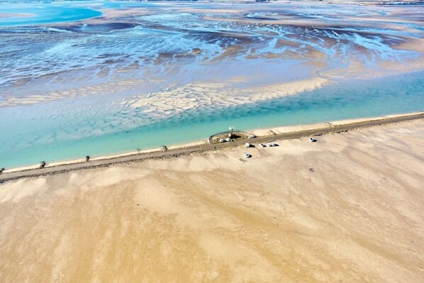 An aerial view of a coastal area with a sandy beach, a road, and a few parked vehicles. - ZEcamping 4* familial pet friendly restaurant et espace aquatique (Soullans)