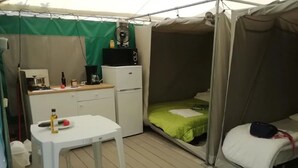 Een tent met een kitchenette, een bed en een tafel.