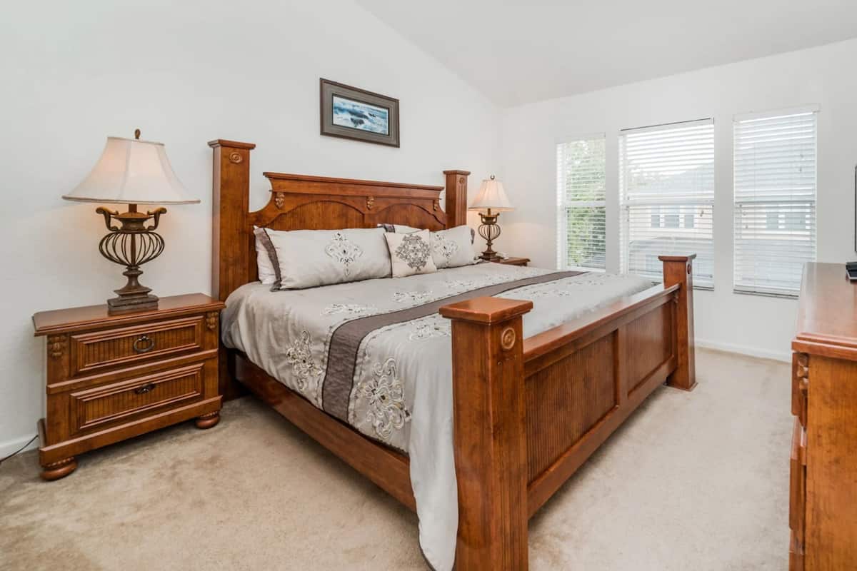 A bedroom with a wooden bed, nightstands, a dresser, and a television.
