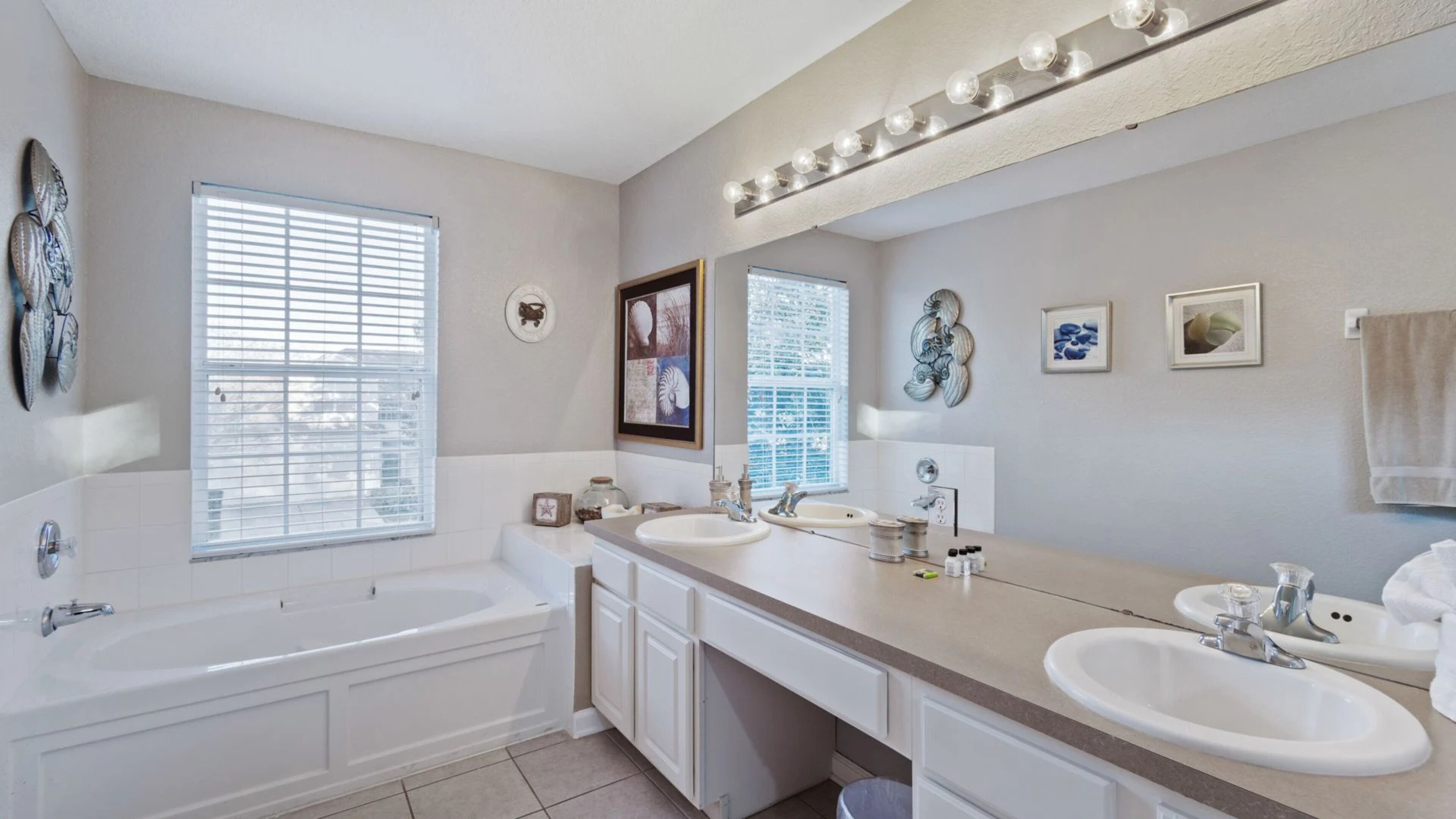 Un bagno con una vasca, due lavandini, un mobile lavabo e un grande specchio illuminato.