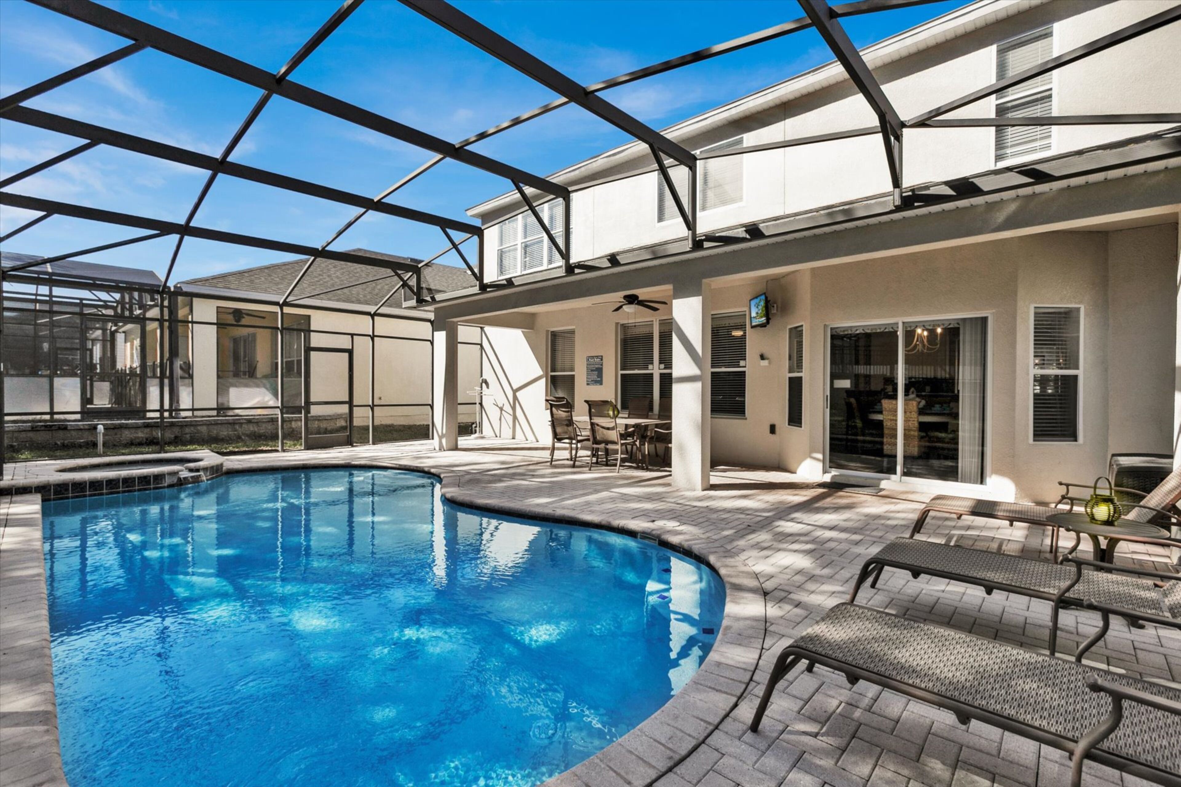 Ein Schwimmbecken mit Glasdach, Sitzgelegenheiten im Freien und einer Terrassenanlage.