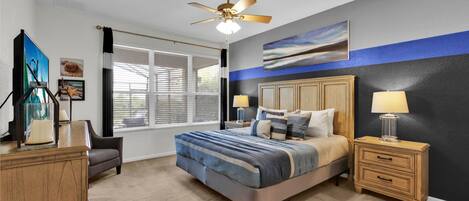Un dormitorio con cama, mesitas de noche, ventilador de techo, ventana con persianas y una obra de arte en la pared.
