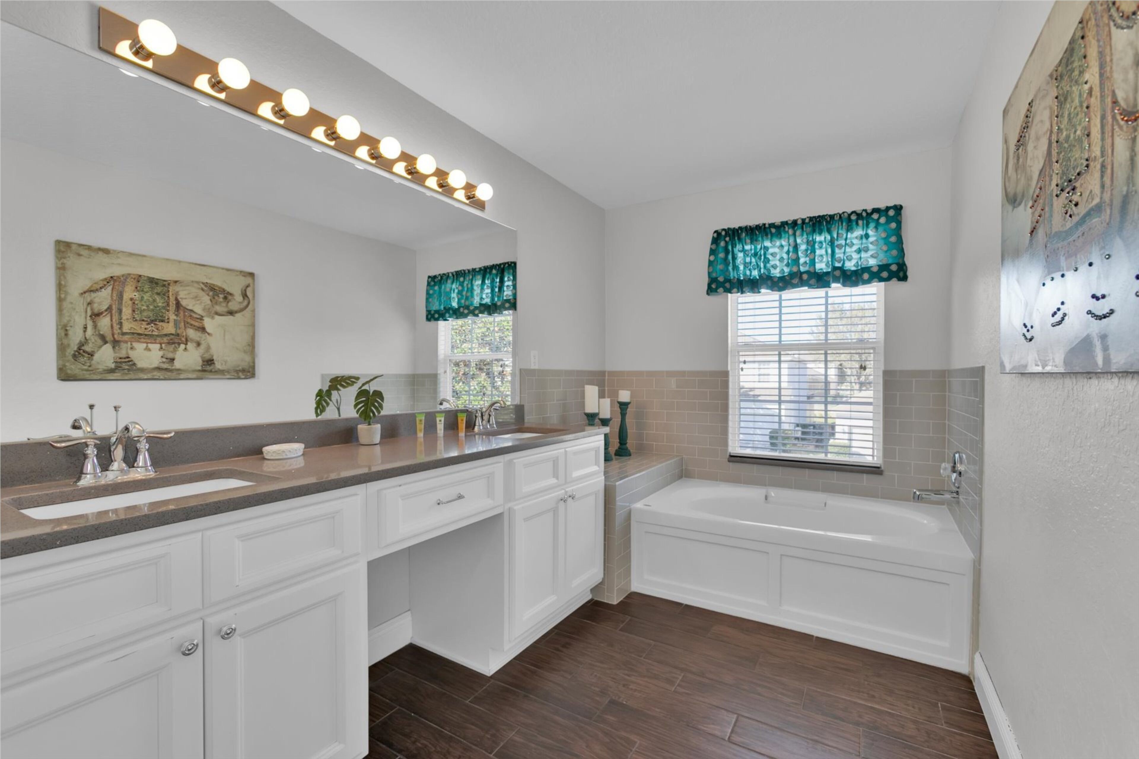 A bathroom with a large vanity, a bathtub, and a window with decorative valance.
