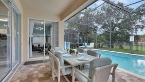 A covered outdoor area with a pool, seating, and a glass door leading to an interior space.
