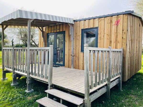 A wooden cabin with a porch, a door, and a window.
