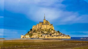 Une vaste structure imposante, digne d’un château historique, avec une tour proéminente, située sur une falaise côtière et offrant une vue dégagée sur la mer.