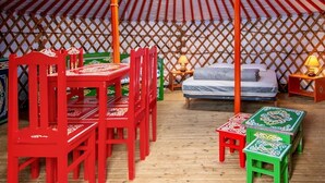 En traditionell jurta med en central träkonstruktion, en säng och en matplats med stolar och bord.
