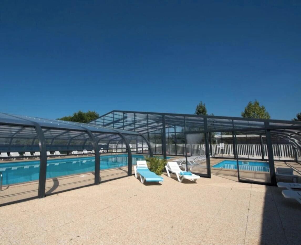 Un espace piscine avec un ciel dégagé, un coin salon abrité et des chaises longues.