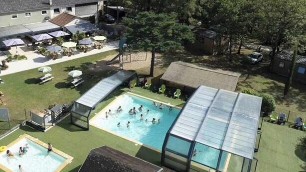 Ett poolområde med flera pooler, en överbyggd sittplats och utsikt över ett bostadsområde.