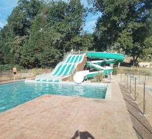 A swimming pool with a water slide and boats.