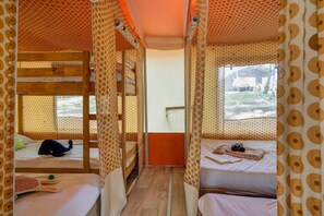 A room with bunk beds, a window with a view, and a wooden ladder.