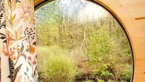 A round window with a view of a grassy area and trees.