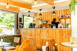 Un área de bar con paneles de madera, una barra con diferentes botellas y sillas de mimbre.