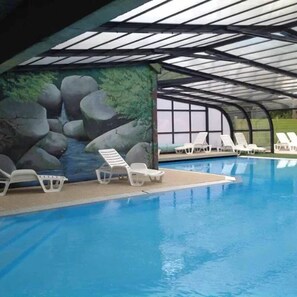 A swimming pool with lounge chairs and a mural of rocks and water.