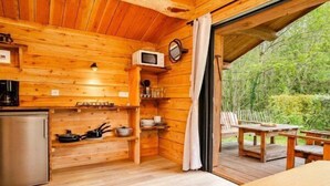 L’intérieur d’un chalet en bois comprend une cuisine, un coin repas et offre une vue sur l’extérieur.