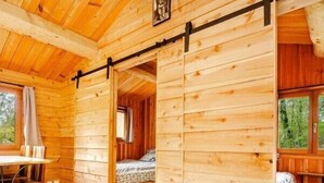 L’intérieur d’un chalet en bois, avec un lit, une table et une fenêtre.