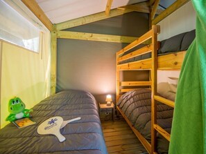 A bunk bed room with a wooden ceiling, a small bedside table with a lamp, and a green plush toy on one bed. - ZEcamping 3 étoiles familial piscine chauffée pet friendly tente 30m2 (Florac)