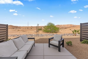A patio with a sofa and chairs, a gravel path, and a view of a desert landscape. - New Luxury Townhome Near Golf, Trails & Casinos Sleeps 8 in charming Mesquite (Mesquite)