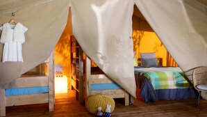 A tented accommodation with a bed, a small table, and a chair. - ZEcamping 3 étoiles piscine locatif 4 pers (Saintes)